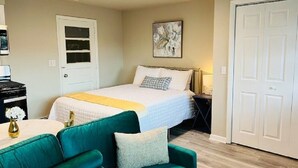 Een slaapkamer met een bed, een groene bank, een bureau met een lamp en een deur.