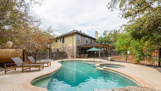 A backyard with a swimming pool, lounge chairs, and a house. - Pool-Hot Tub-Putting Green-Arcade-Oasis (Austin)