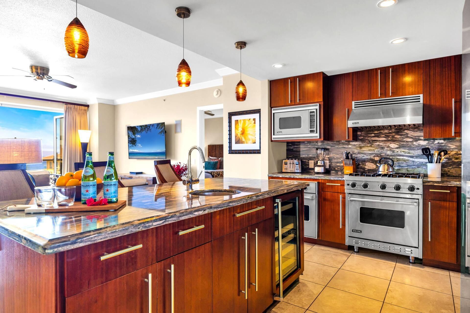 A modern kitchen with wooden cabinets, stainless steel appliances, and a marble countertop.