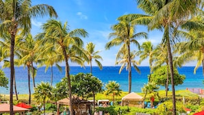 A tropical resort with palm trees, beach umbrellas, and a view of the ocean. - Honua Kai Konea Resort by KBM (Kaanapali)