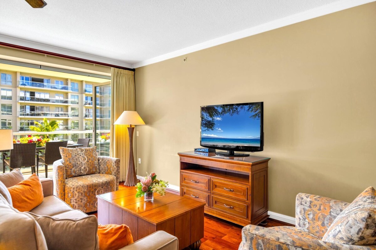 Une chambre d’hôtel avec un balcon, une télévision, un canapé, une table basse et une lampe.