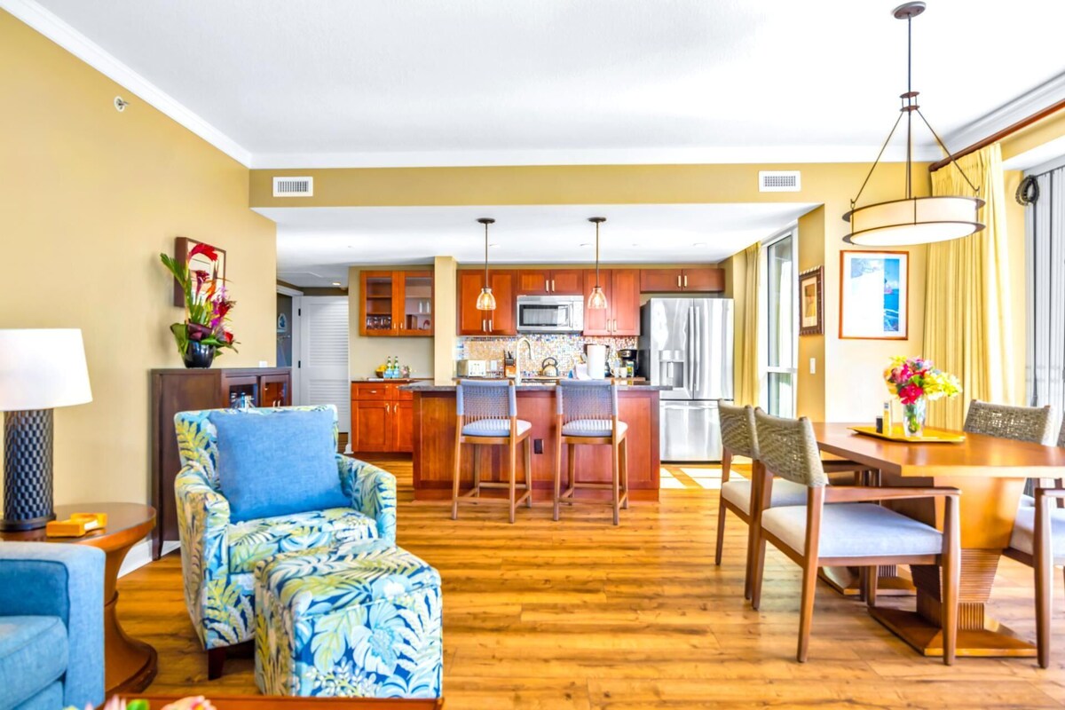 A modern living room with a blue patterned sofa, wooden dining table, and chairs.