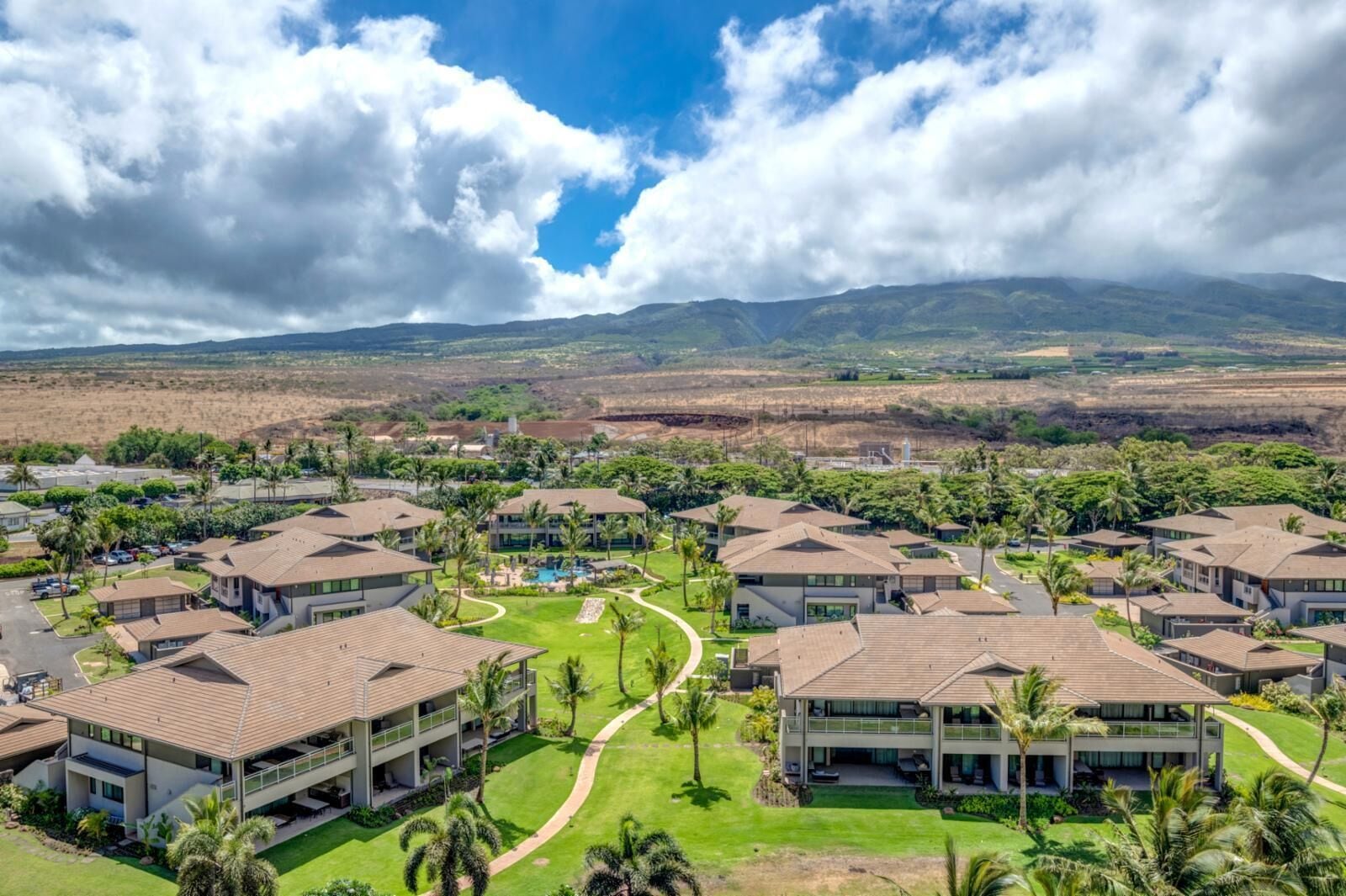 A resort with multiple buildings, a swimming pool, and a view of distant mountains.