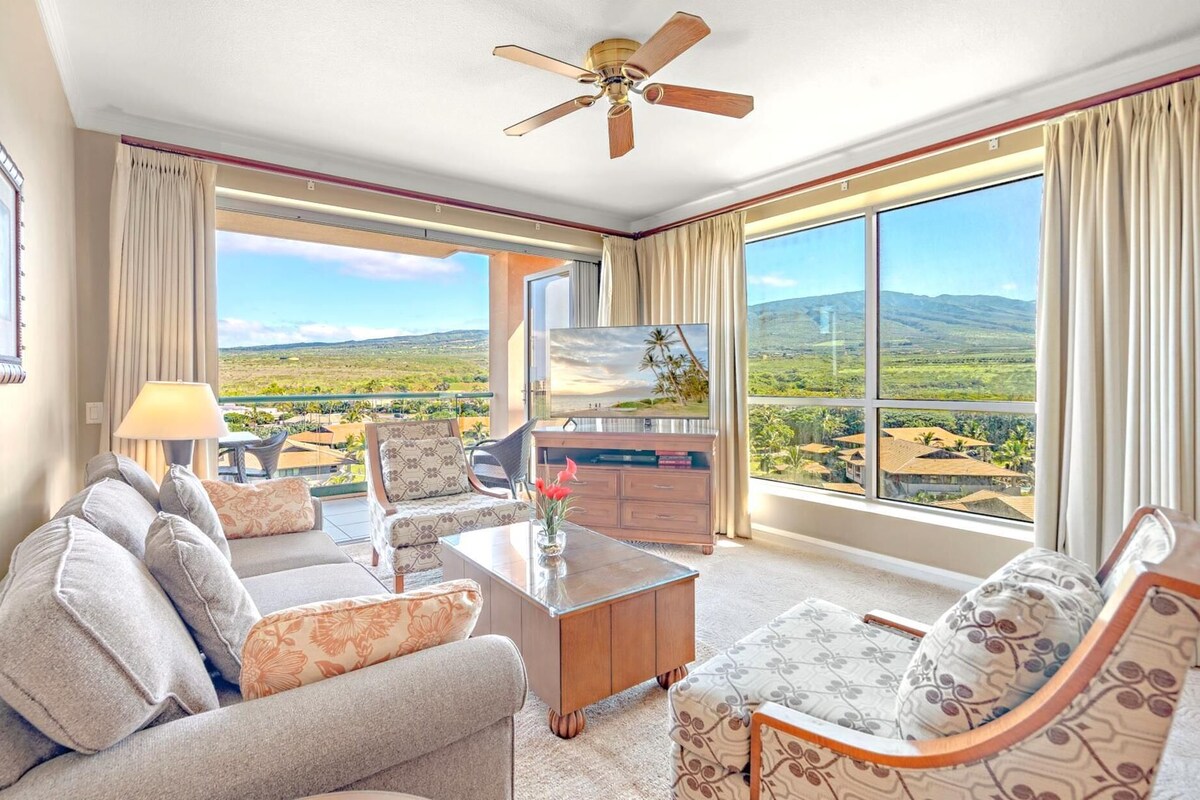 A spacious living room with a large window offering a scenic view of a mountainous landscape.