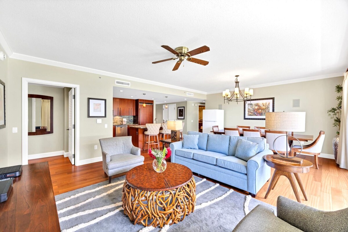 A spacious living room with a blue sofa, a wooden coffee table, and a ceiling fan.