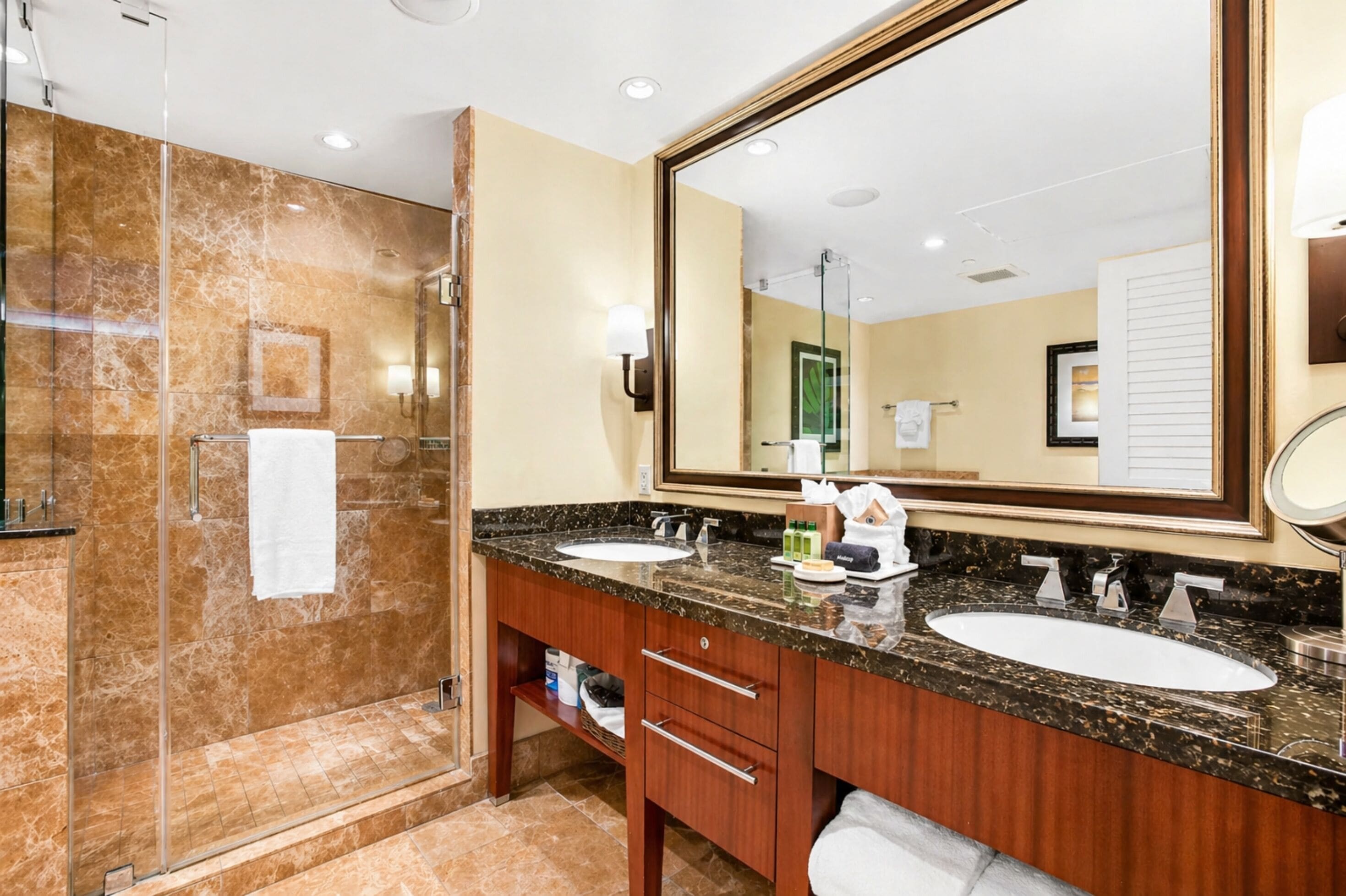 A bathroom with two sinks, a large mirror, and a glass shower enclosure.