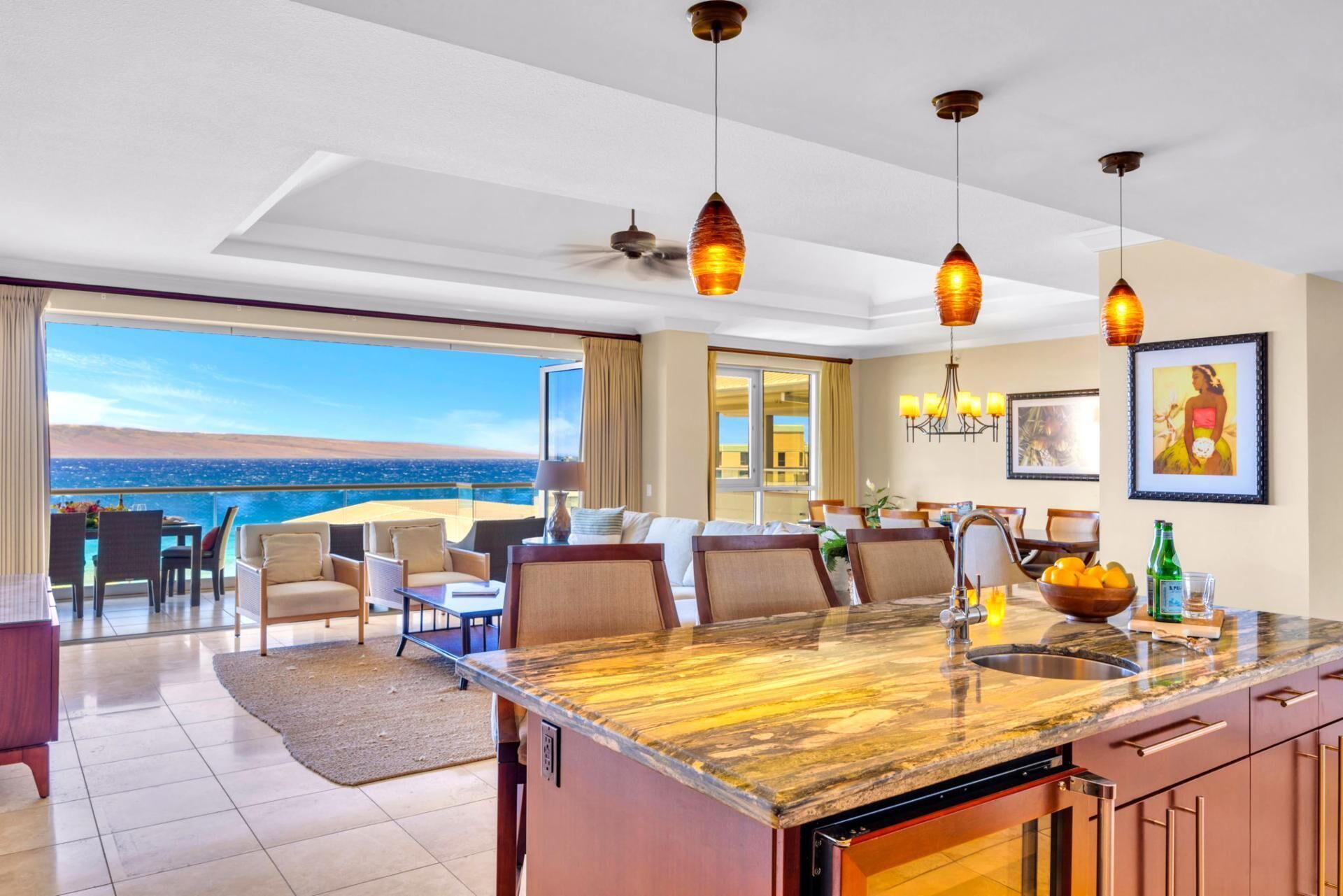 A modern kitchen with a marble countertop, a dining area with a view, and a ceiling fan.