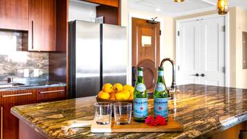 Una cocina con encimera de mármol, un refrigerador y un cuenco de limones.