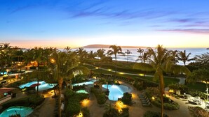 A resort with multiple swimming pools, palm trees, and a view of the ocean at sunset. - Honua Kai Konea Resort by KBM (Kaanapali)