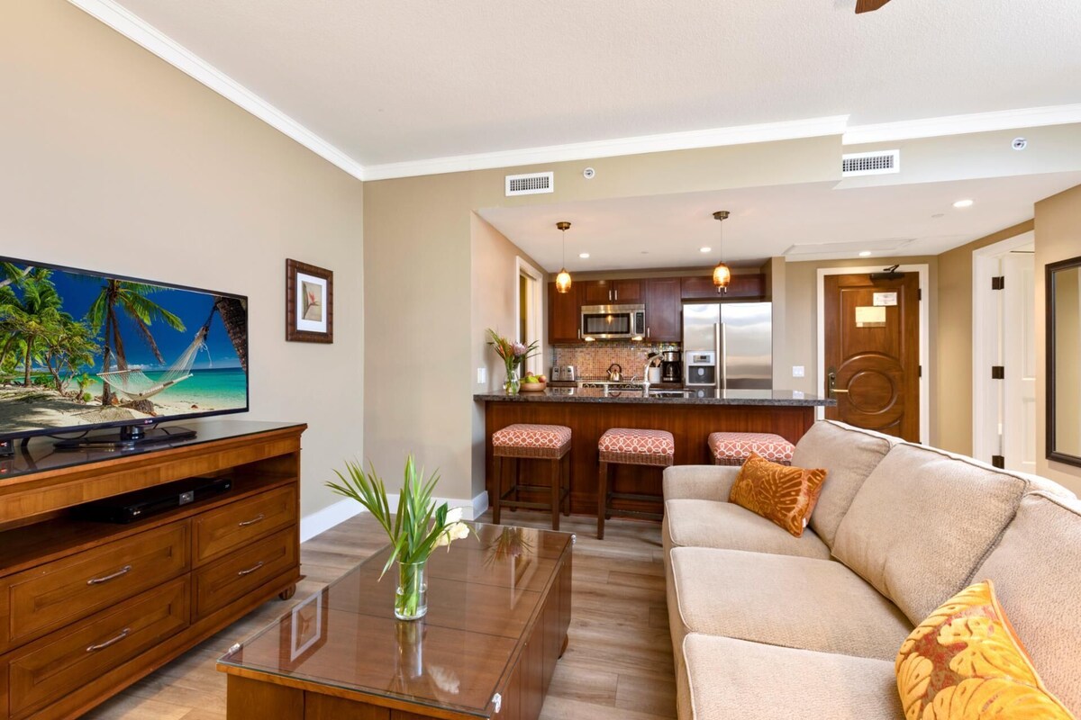 A modern living room with a flat-screen TV, a wooden coffee table, and a beige sofa.