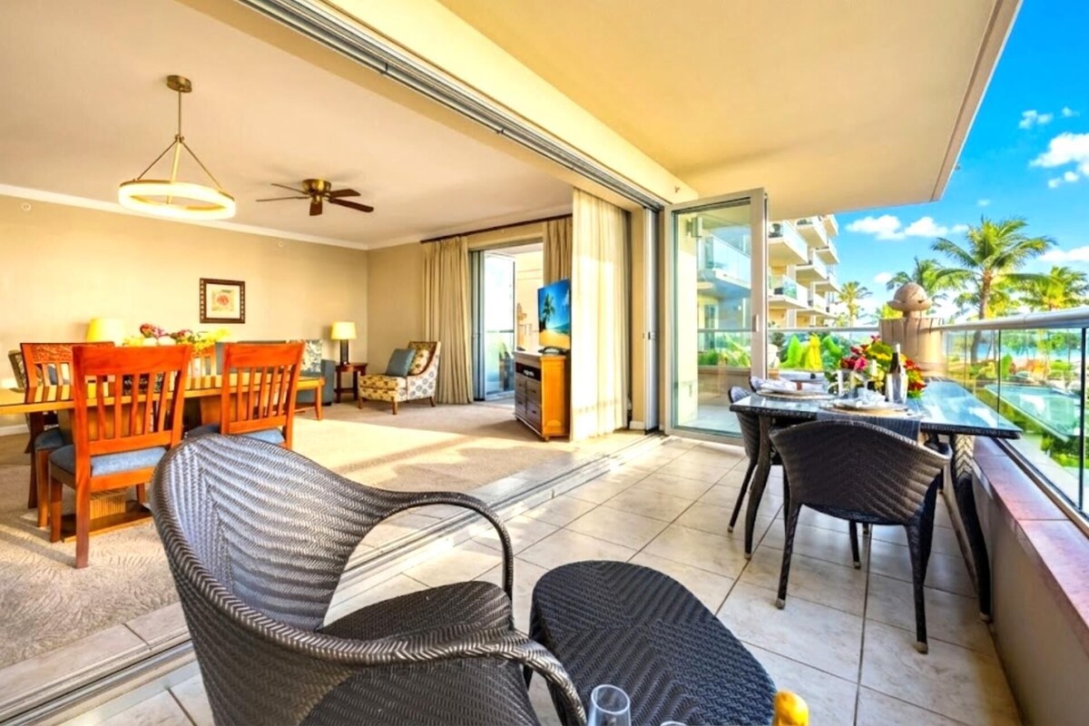 Un balcon avec des fauteuils en osier et une table à manger, donnant sur une piscine et les bâtiments du complexe hôtelier.
