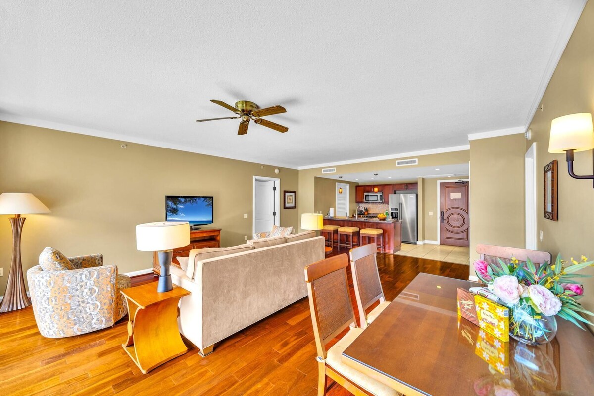 A modern living room with a sofa, a dining table, and a kitchen in the background.