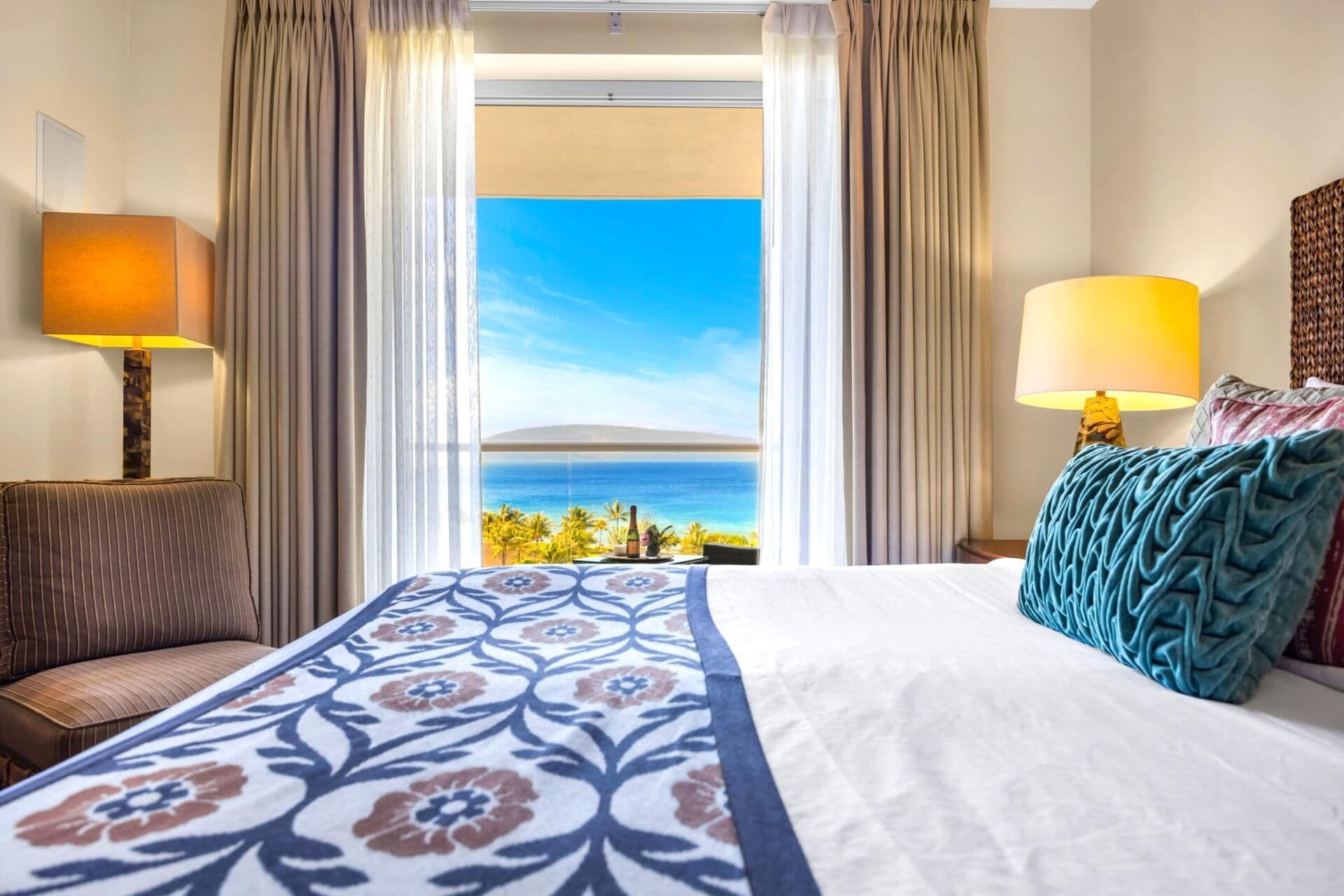 Une chambre d’hôtel avec un lit, une table de chevet, une lampe et une vue sur l’océan.