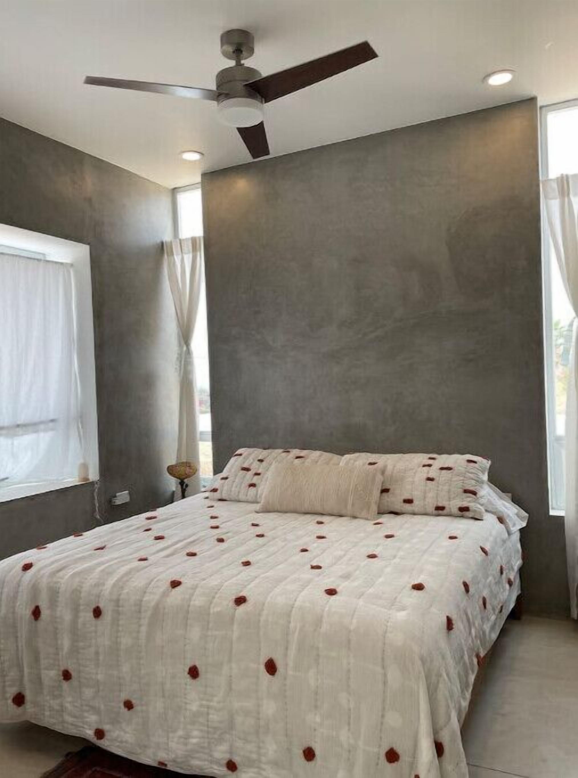 A bedroom with a bed, a ceiling fan, and a window with curtains.