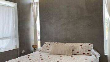 A bedroom with a bed, a ceiling fan, and a window with curtains.