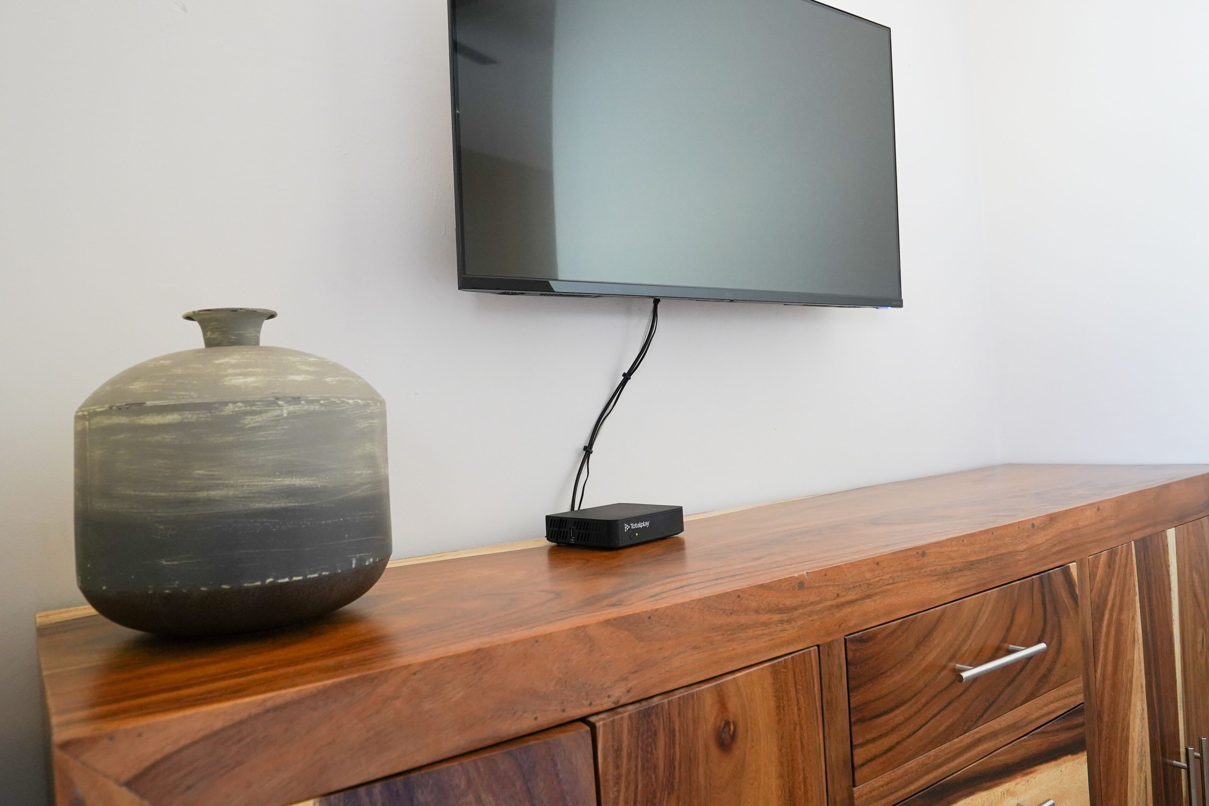 Un mobile in legno con un vaso e un televisore a schermo piatto montato a parete.