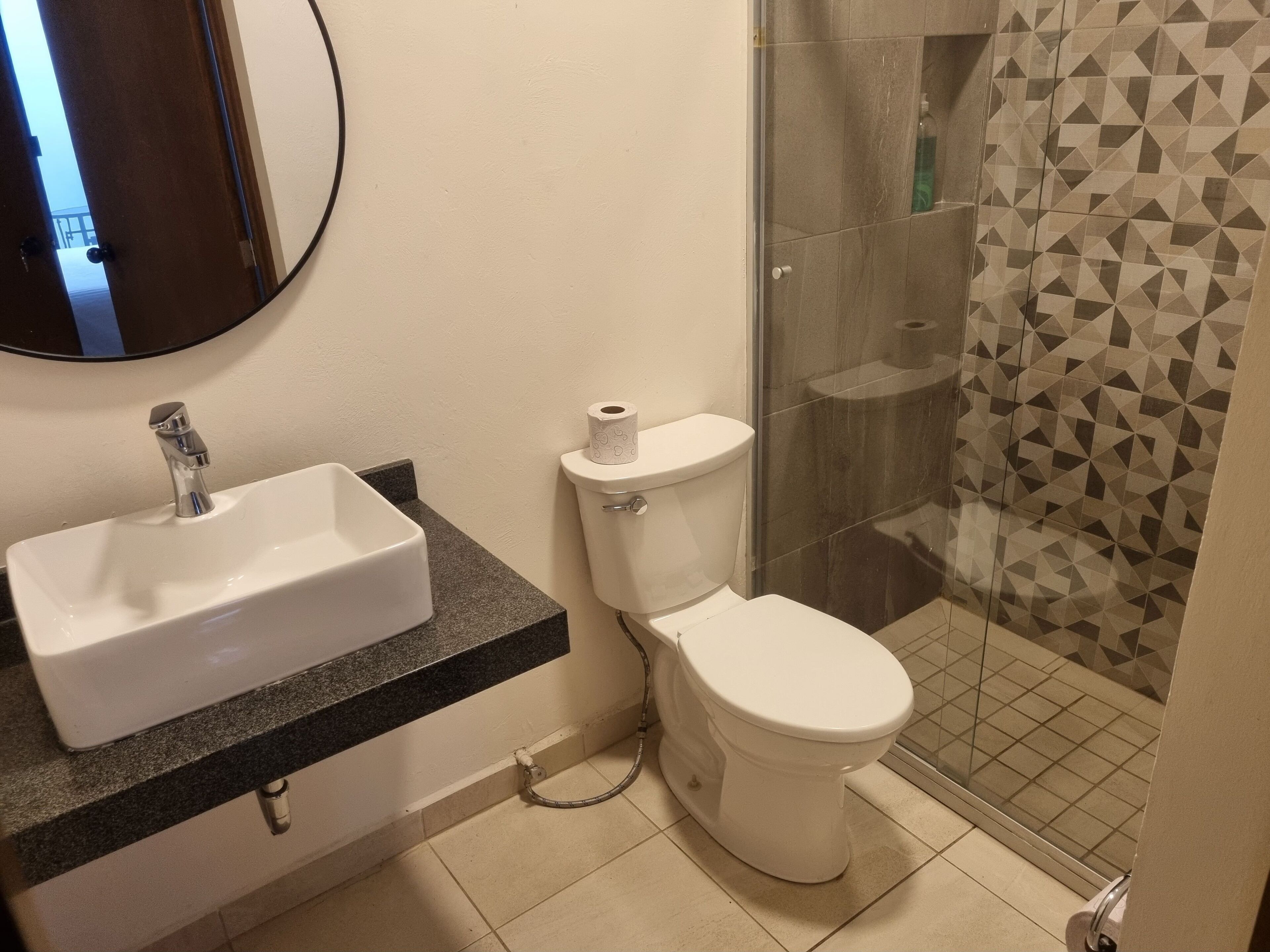 Et badeværelse med hvid vask, toilet og bruser.