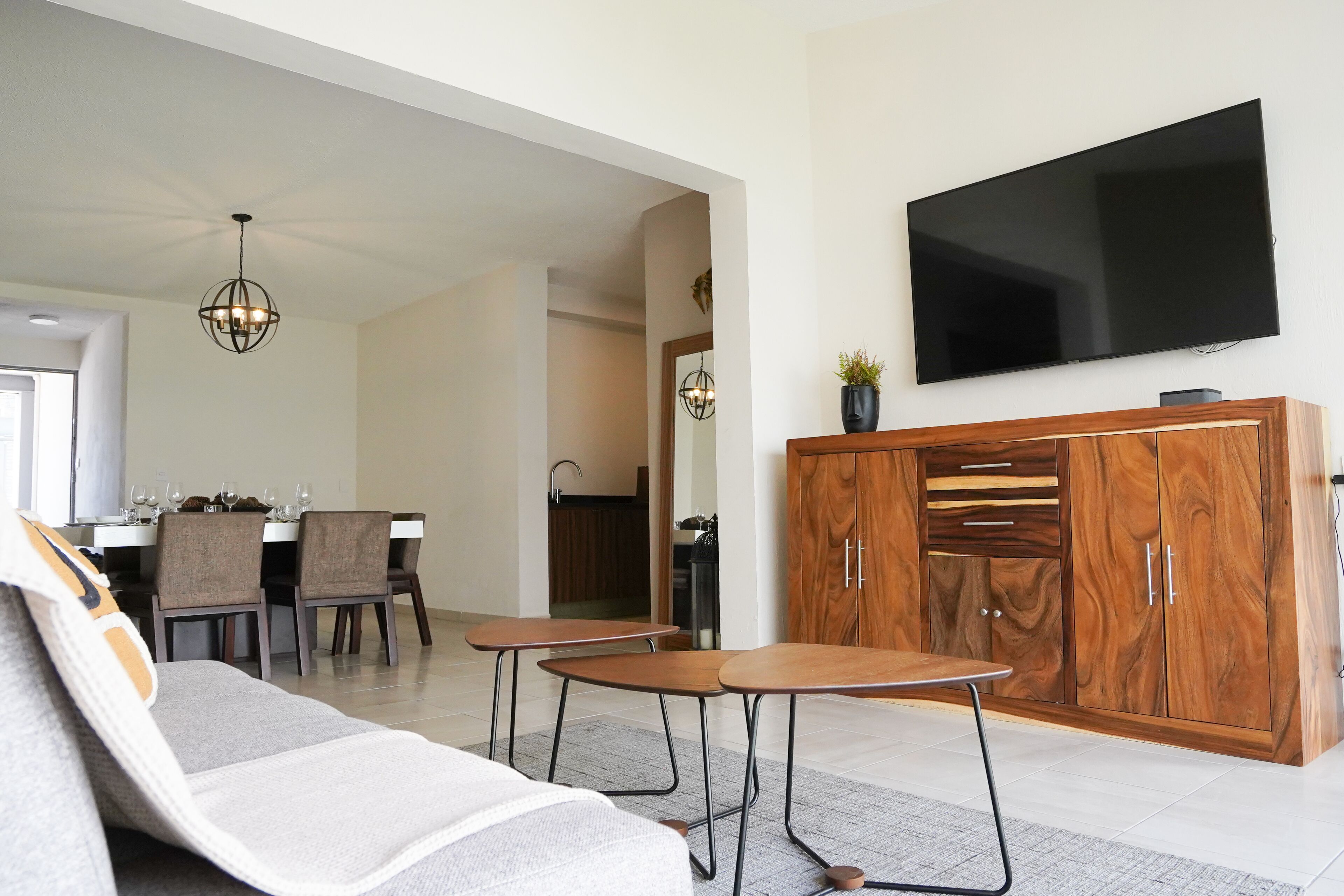 Una sala de estar moderna con un sofá, dos mesas, un televisor y un mueble de madera.