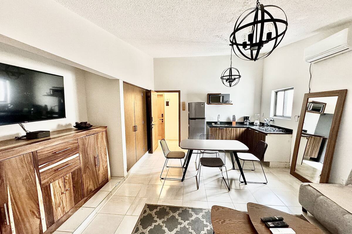 A modern kitchen with a dining area, a flat-screen TV, and a large mirror.