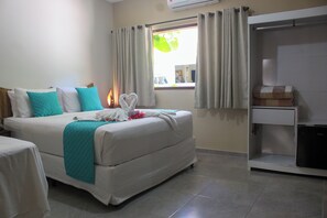 A hotel room with a bed, a desk, and a window with curtains. - Pousada Villabougainville (Maragogi)