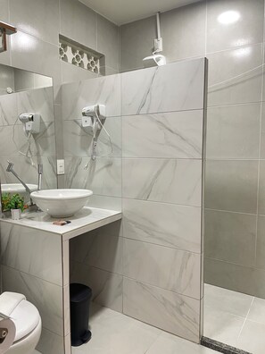 Een badkamer met een wit wastafelmeubel, een spiegel, een haardroger en een douche.
