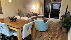 A modern living room with a wooden dining table, light blue armchairs, a sofa, and a coffee table.