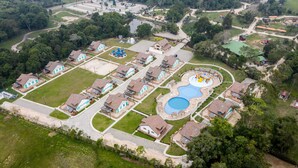 An aerial view of a residential area with houses, a playground, and a swimming pool.