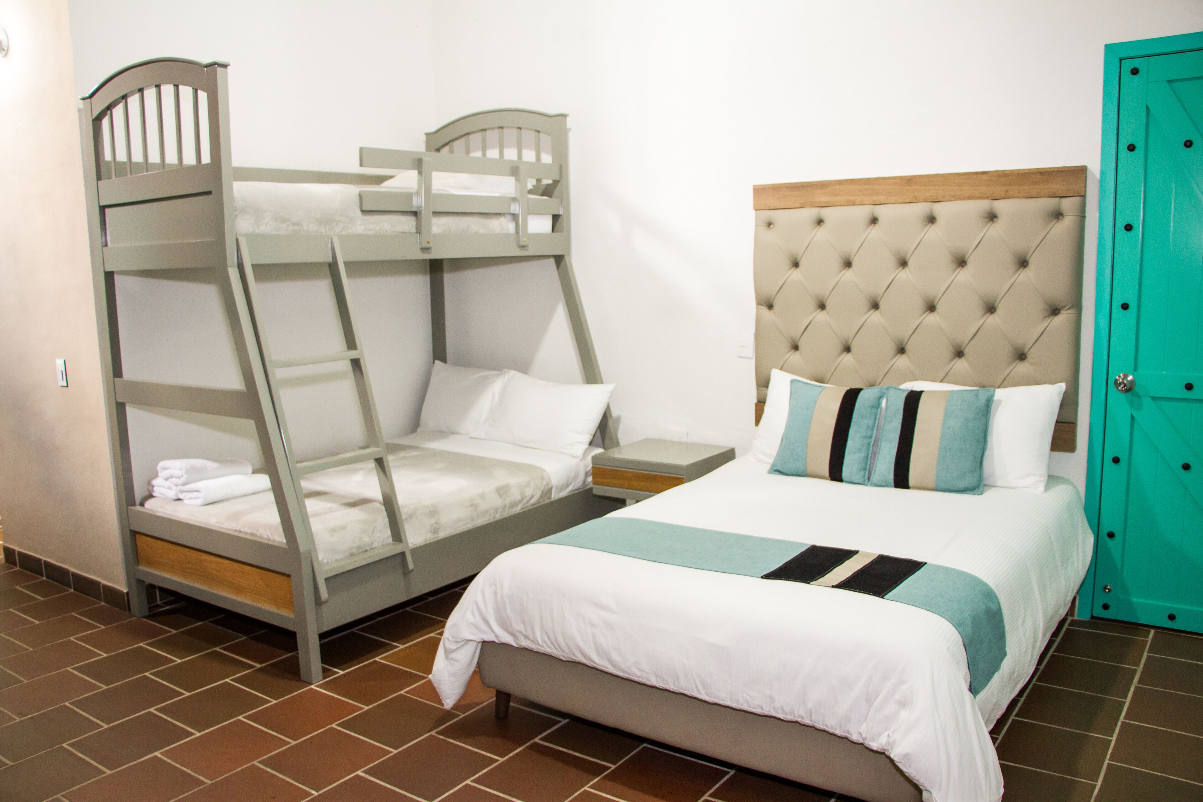 Una habitación con literas, una cama individual y una puerta.