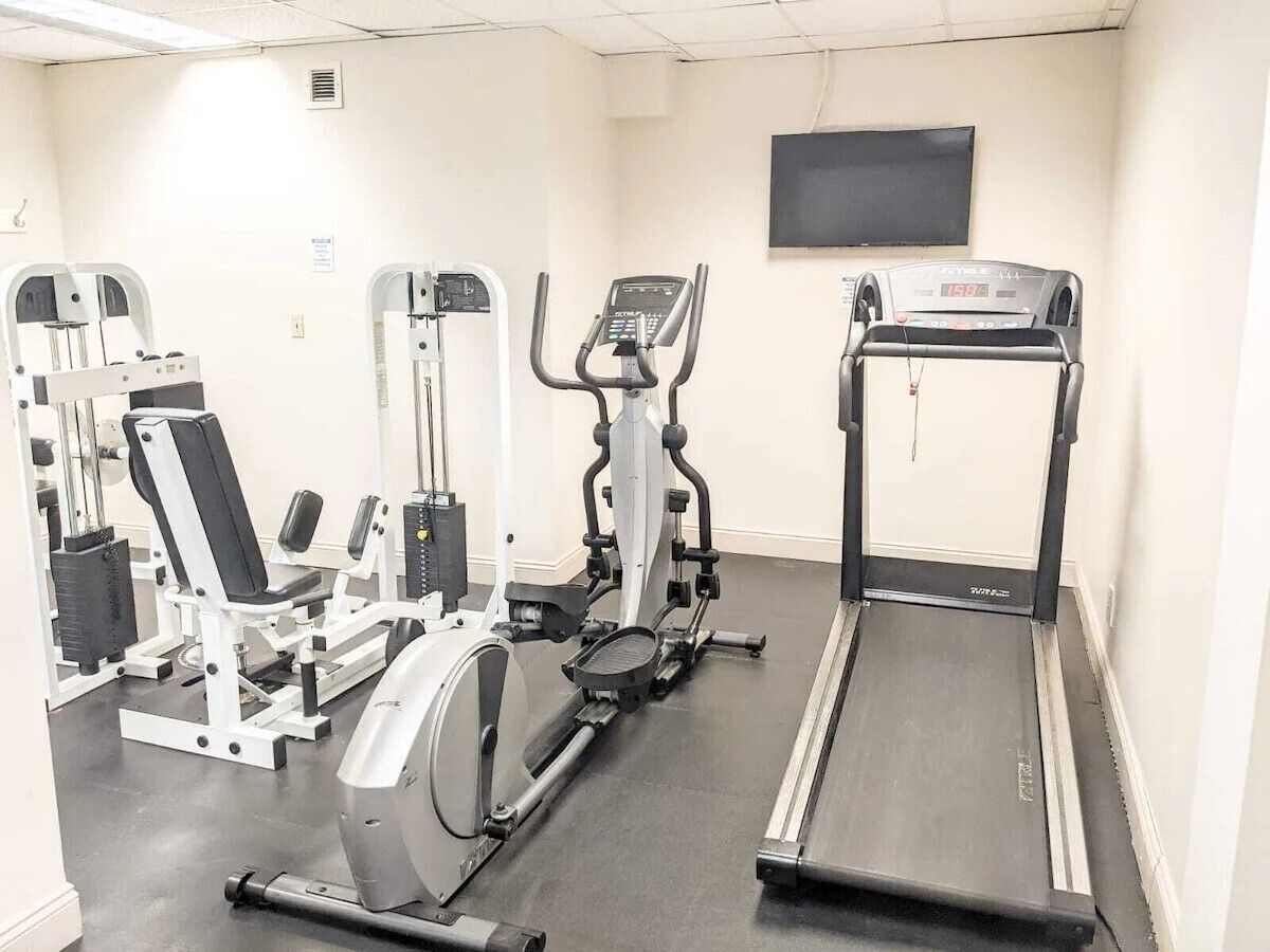 Een fitnessruimte met cardio-apparaten, gewichtstrainingsapparatuur en een televisie aan de muur.