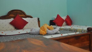 A bed with a wooden headboard, red and white pillows, and a stuffed animal. - La Jungle Vista sigiriya (Sigiriya)