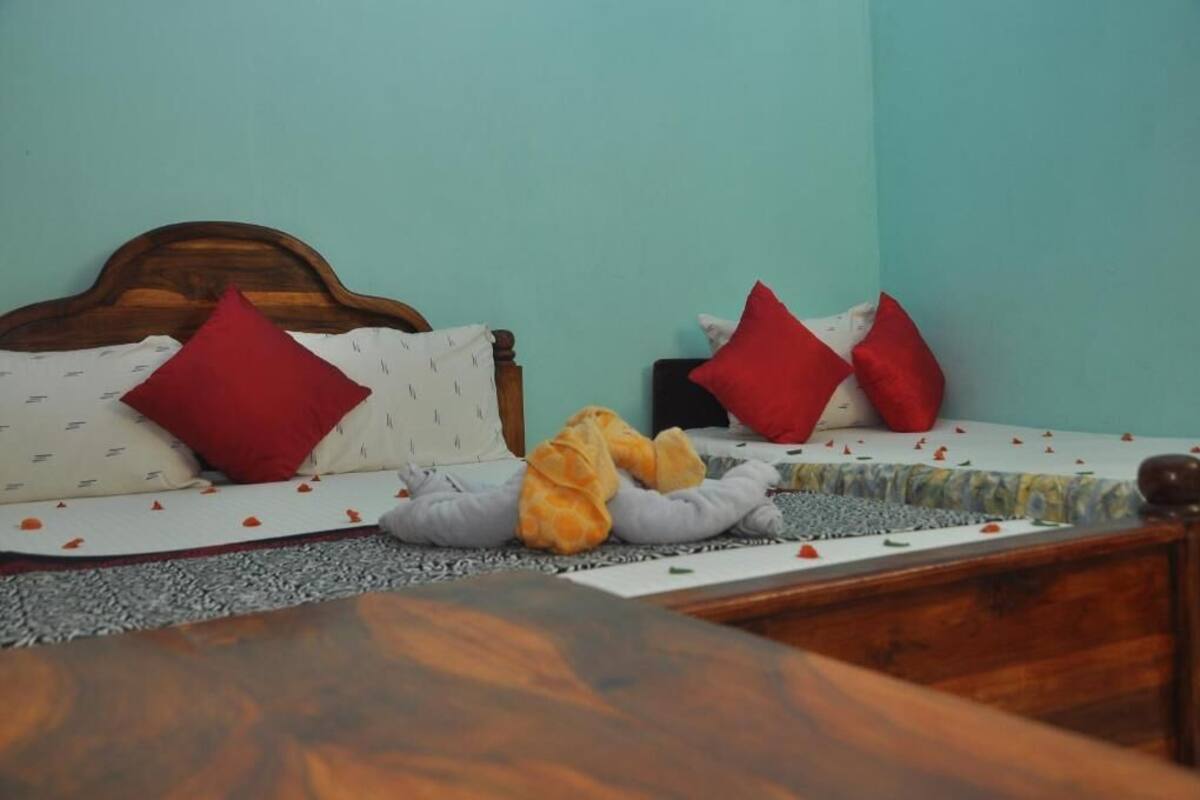 Ein Bett mit Holz-Kopfteil, roten und weißen Kissen sowie einem Stofftier.