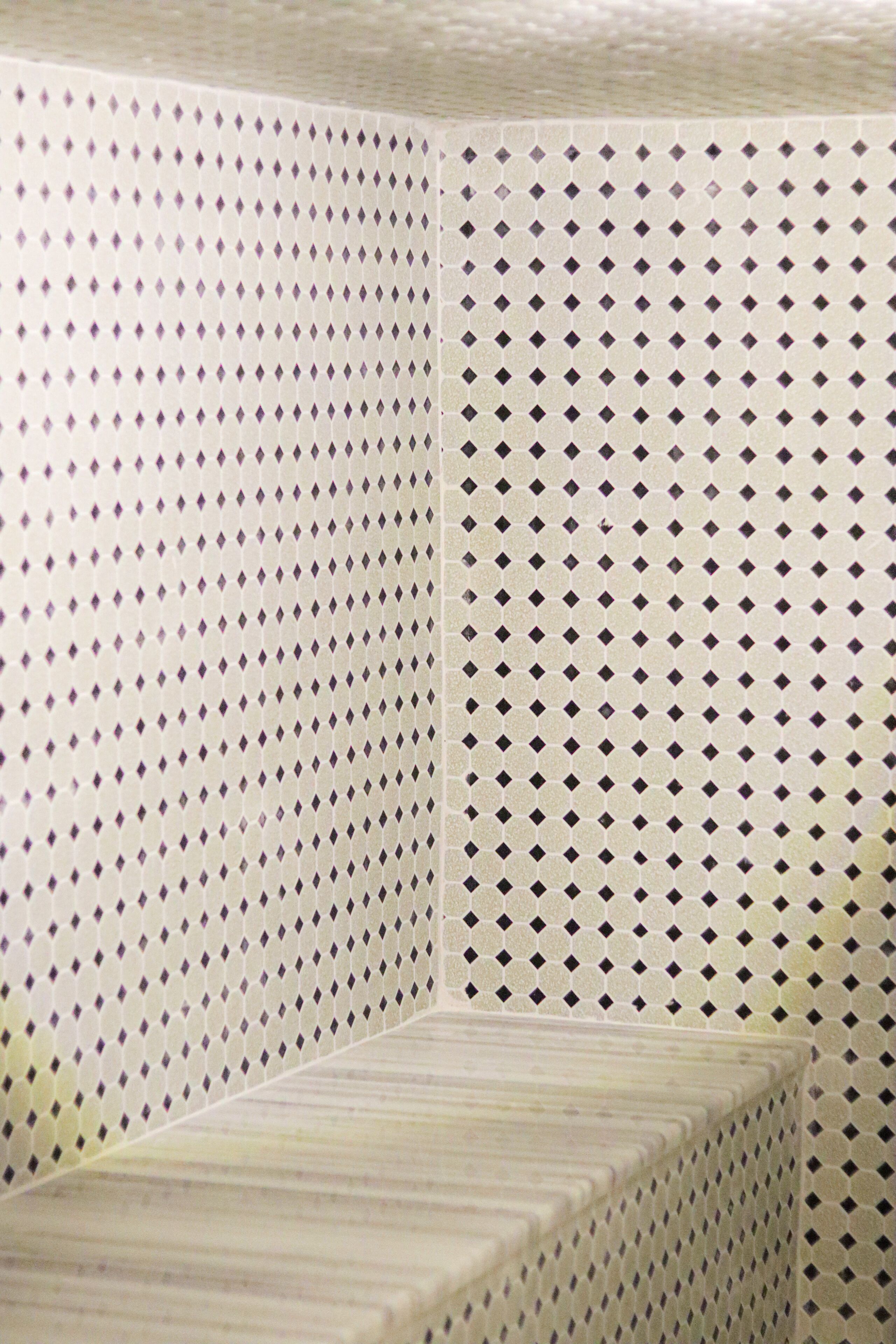 A corner of a room with a tiled wall featuring a diamond pattern.