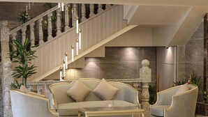 Un vestíbulo espacioso con una imponente escalera, un sofá cómodo y elegantes sillas.