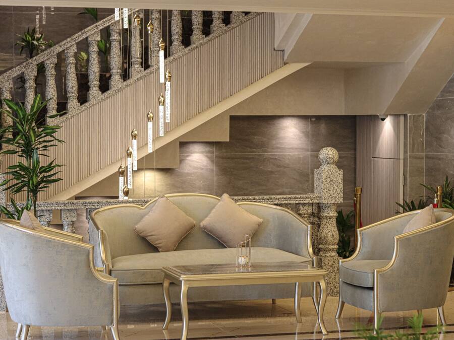 A spacious lobby with a grand staircase, a plush sofa, and elegant chairs.