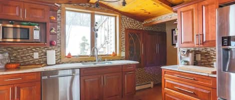 A kitchen with wooden cabinets, stainless steel appliances, and a large window.