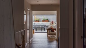 A hallway leading to a dining area with a table and chairs, a sofa, and potted plants. - Little Beach House by Bloom Stays -  a holiday let that sleeps 8 guests  in 3 bedrooms (Whitstable)