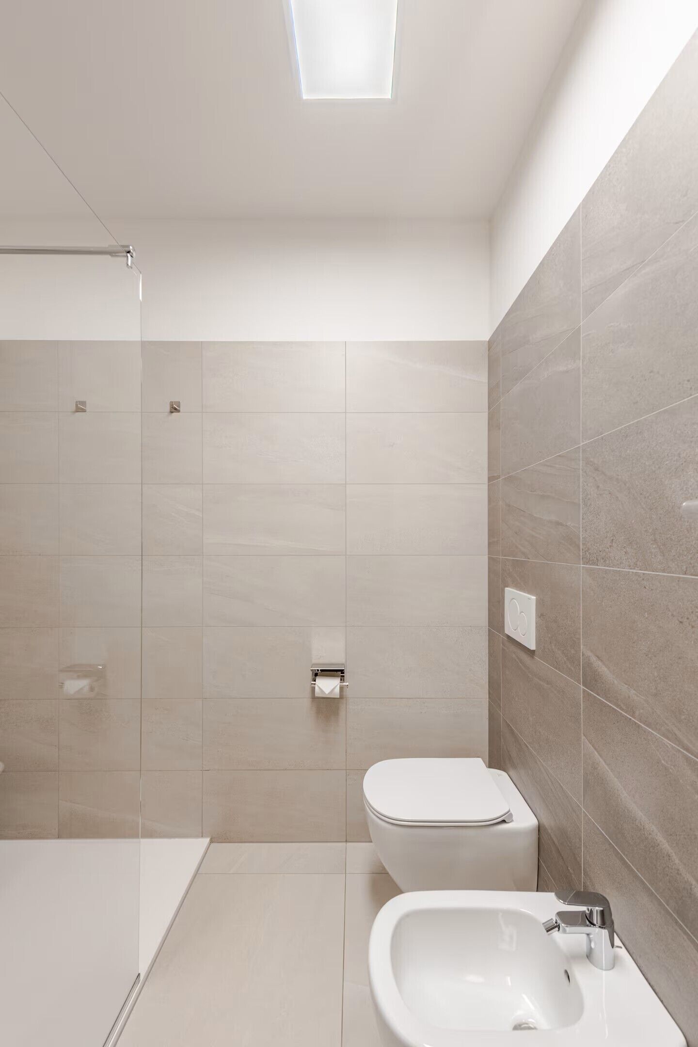 A modern bathroom with a shower, toilet, and sink.