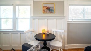 A dining area with a round table, two white chairs, a candle, and a framed picture on the wall. - Charming Studio Balboa Park W/D (San Diego)
