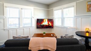 A living room with a fireplace, a TV mounted above it, and a cozy seating area with a sofa and a table. - Charming Studio Balboa Park W/D (San Diego)