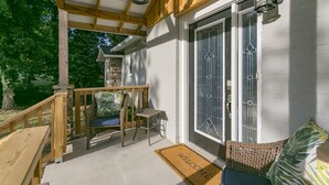 Een overdekte veranda met rieten meubilair, een welkomstmat en decoratieve lantaarns.