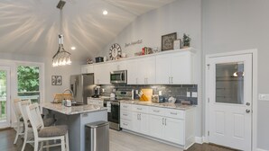 Een moderne keuken met witte kasten, roestvrijstalen apparatuur en een centraal eiland met zitplaatsen.