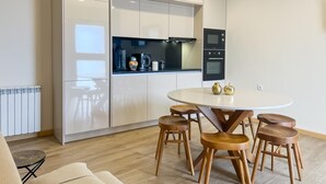 Une cuisine moderne avec une table de salle à manger ronde et des tabourets en bois, équipée d’un four et d’un micro-ondes encastrés.