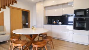 Une cuisine moderne avec des meubles blancs, un micro-ondes noir et une machine à café.