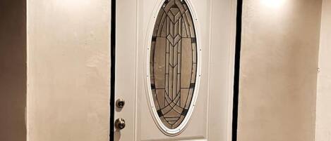 Une porte blanche ornée d’un panneau de verre décoratif et de deux petits panneaux situés en dessous.
