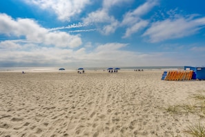 Una playa con arena, sombrillas y sillas de playa.