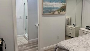 A bedroom with a bed, a dresser, a mirror, and a painting of a beach scene. - New Private house in historic area- Pasadena (Pasadena)