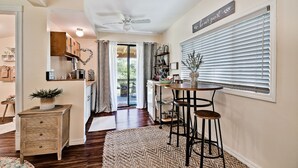 A cozy kitchen with a wooden table and stools, a ceiling fan, and a sign that says "be our guest".
