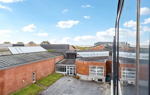 A view of a building with multiple roof levels, including a flat roof with solar panels and a brick building with large windows.