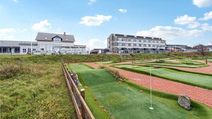 A golf course with a clubhouse and residential buildings in the background. - 1 bedroom beach front apartment in Fanø (Fanø)