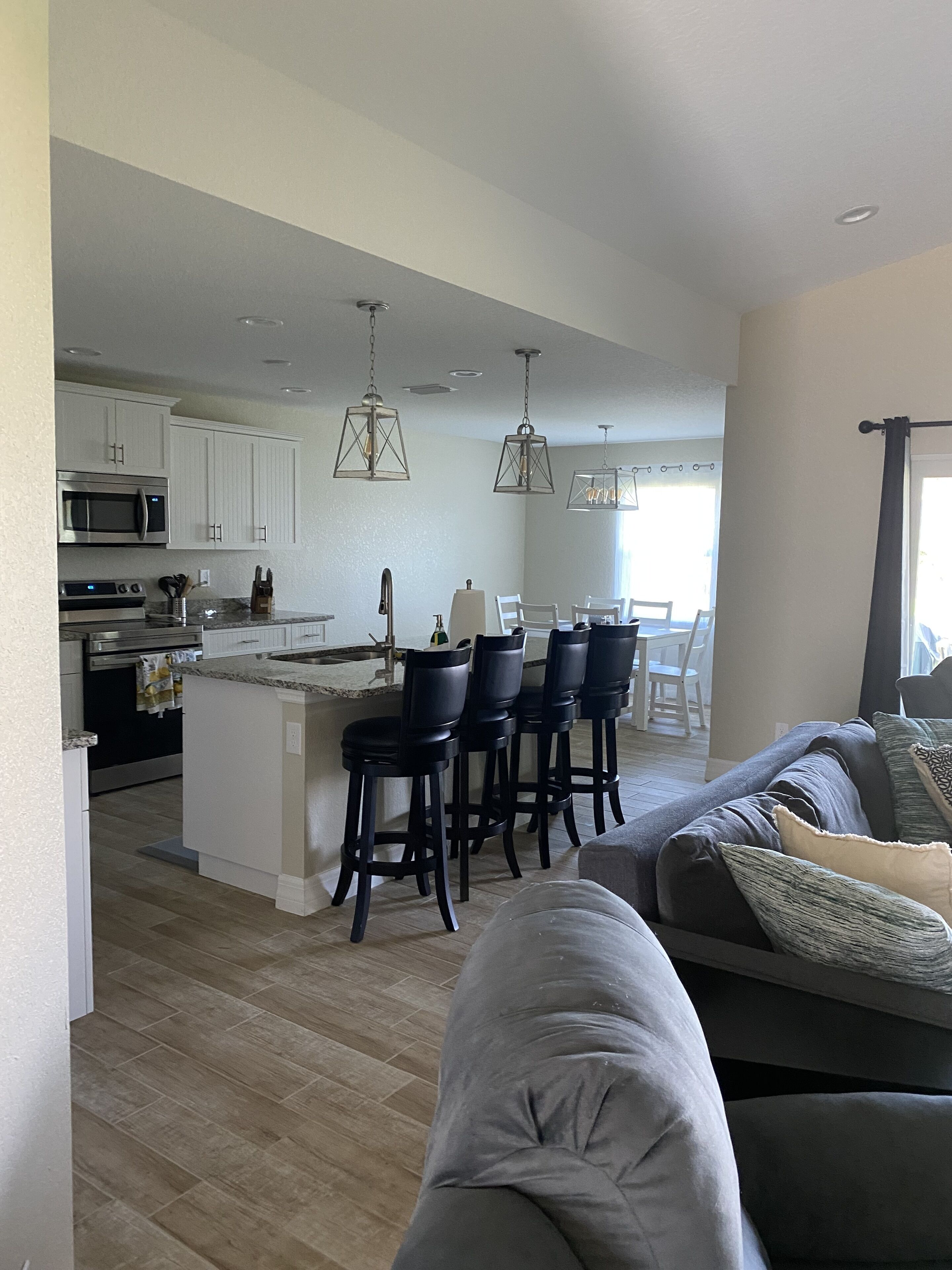 A modern kitchen with white cabinets, a central island with bar stools, and pendant lighting.